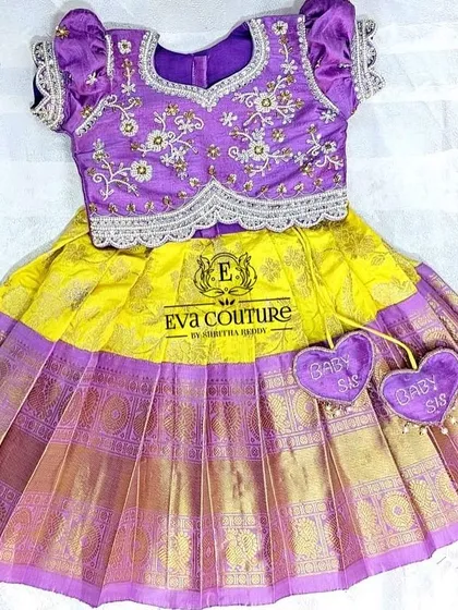 A newborn Pattu lehenga in yellow and purple, complete with cute "Baby Sis" heart tassels. This is a ready-to-ship item.