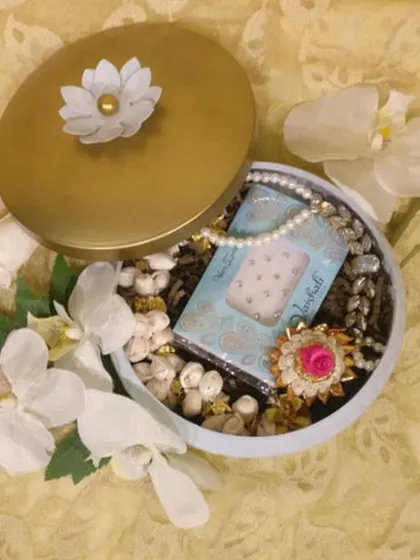A closer look at one of my curated Mehendi favour boxes. The gold-lidded box is filled with a pearl necklace, a floral ring, and other small trinkets.