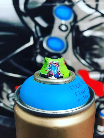 A macro shot of a used spray can nozzle, covered in the history of past projects. Every artist has their favorite tools, and these caps are essential for creating different line widths and effects in my graffiti art.