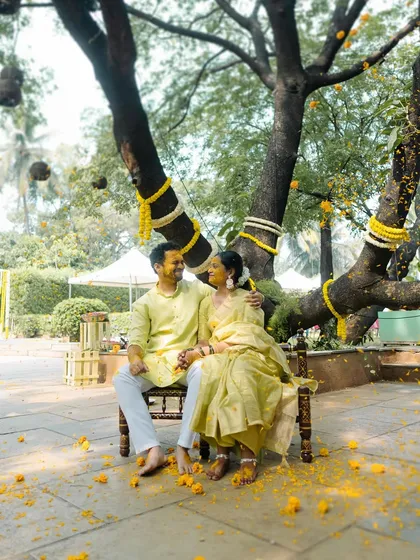 A serene portrait of the couple under a beautifully decorated tree during their Haldi ceremony. This quiet moment provides a lovely contrast to the usual playful chaos.