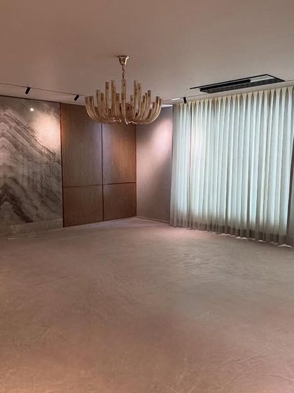 Handover day at the Noida penthouse. The living room is empty but complete, showcasing the bookmatched marble feature wall, track lighting, and floor-to-ceiling curtains.
