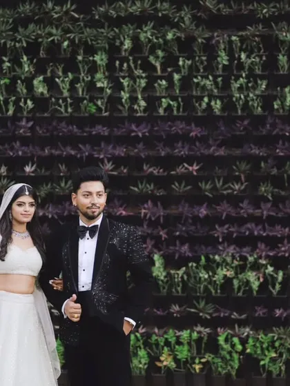 A stylish portrait of the couple against a green wall. Their black and white outfits create a striking contrast, resulting in a modern and chic engagement photo.