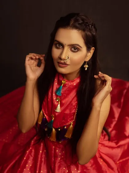 A modern take on a traditional look. The red dress with a unique, tassel-detailed neckline is shot against a dark background to make the colors pop.