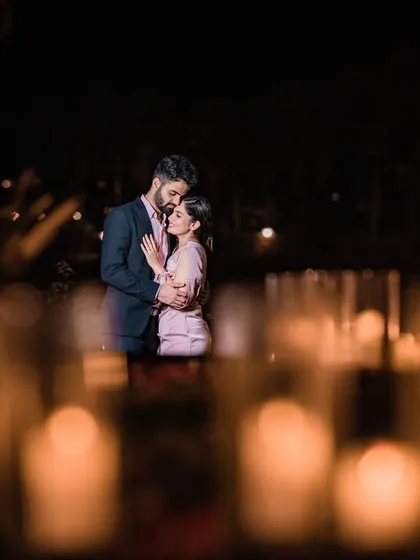 An artistic shot of the couple embracing, viewed through a field of glowing candles that we arranged to create a dreamy, romantic atmosphere.