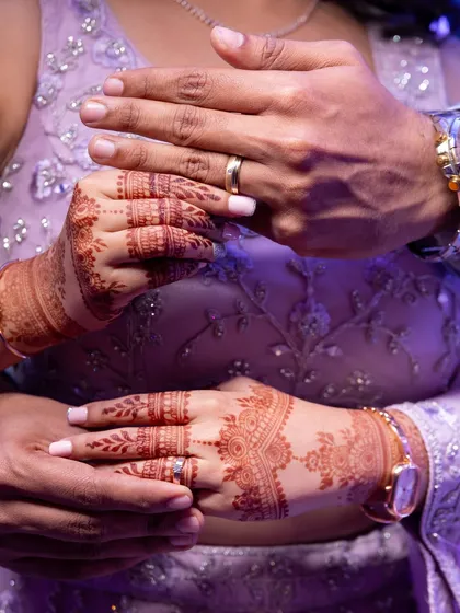 A beautiful shot of the couple's hands, adorned with rings and henna.