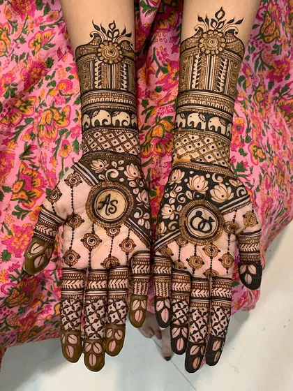 A close-up of a personalized engagement mehndi with the couple's initials. The design is rich with traditional patterns, including elephant processions and lotus flowers.