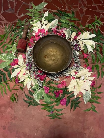A beautiful arrangement of flowers and leaves cradling a singing bowl before a session. This ritual honors the sacred elements of nature and sets an intention of healing and peace for the practice.