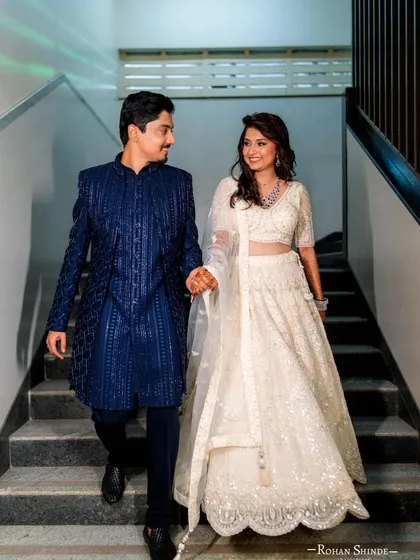 A real-life fairy tale moment for one of our lovely couples. She is wearing a delicate white sequined lehenga and he complements her perfectly in a textured royal blue bandhgala. This is a perfect example of how we style coordinated looks for wedding receptions.