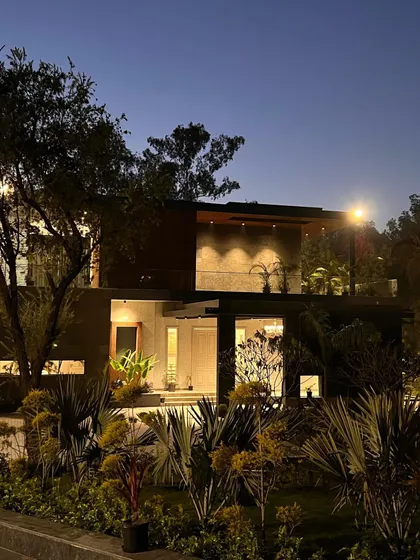 'The One' residence at night, nestled in its lush landscape. The strategic lighting highlights the home's contemporary form, with warm light spilling from the large glass windows.