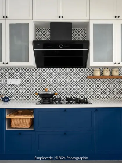 A close-up of the cooking area in the 'Cover me in Sunshine' kitchen, showing the patterned backsplash, black chimney, and custom cabinetry with small, elegant knobs.