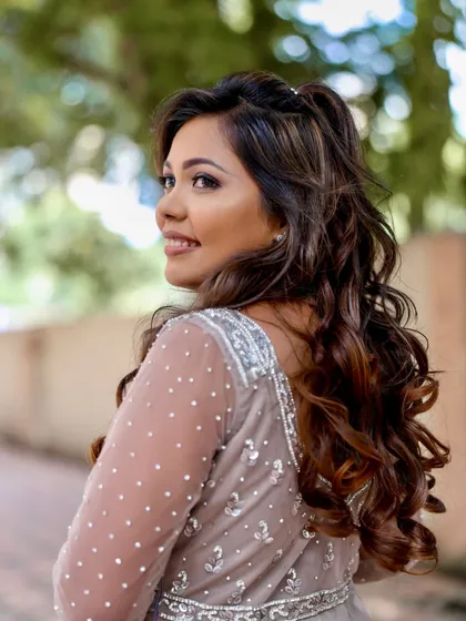 A side profile that highlights the soft curls and the radiant glow of her skin. A truly elegant reception look.
