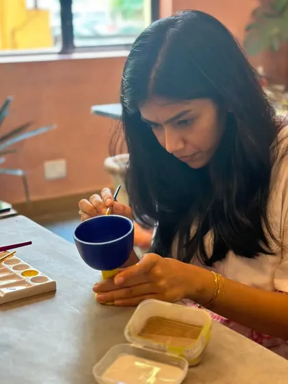 The final touches. A student carefully paints her handmade piece, adding her personal style before it goes into the kiln.