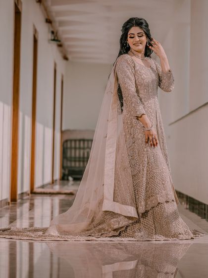The bride looks down at her flowing gown, captured in a full-length shot that emphasizes the elegance of her attire.