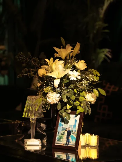 For the 'Jungle Disco' sangeet, coffee tables were personalized with the couple's photos, fresh white lilies, and modern crystal lamps, adding an intimate and personal touch to the glamorous setting.