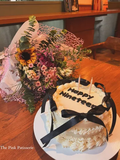 A minimalist "Happy Nineteen" cake with elegant black ribbons, perfect for a stylish celebration.