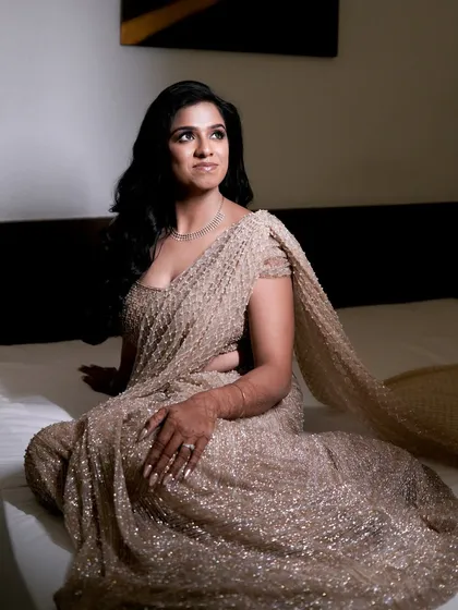 A glamorous reception look featuring a sparkling gold saree and subtle smokey eyes.
