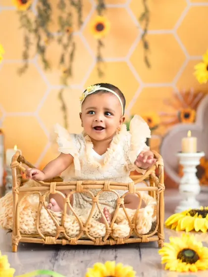 A joyful baby sits in a wicker bassinet surrounded by sunflowers. This photo showcases the variety of props we use within a single theme to create different looks.