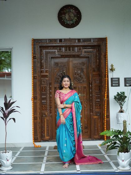 This traditional look in front of a carved wooden door shows the timeless elegance of a Nauvari saree.