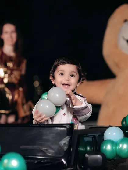 A playful moment captured during a birthday party. The birthday boy is having a great time playing with balloons, a perfect candid shot.
