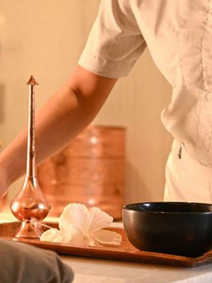 Every element of your treatment is thoughtfully prepared. A tray holds a floral water bowl and a traditional copper vessel, details that honor the ancient wellness practices that inspire my therapies.