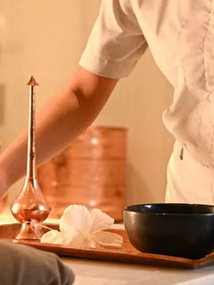 Every element of your treatment is thoughtfully prepared. A tray holds a floral water bowl and a traditional copper vessel, details that honor the ancient wellness practices that inspire my therapies.