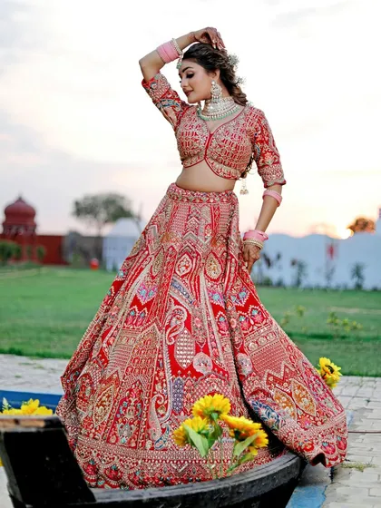 A bride in a stunning red lehenga poses in a boat filled with sunflowers on our pond. This setup combines our water feature and props to create a unique and vibrant bridal portrait.