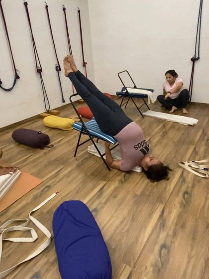 A student in a supported shoulder stand using a chair. This variation is less strenuous on the neck and is a part of our restorative sequences.