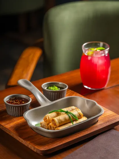 Crispy spring rolls served in a modern skillet with dipping sauces for Camo, Noida.