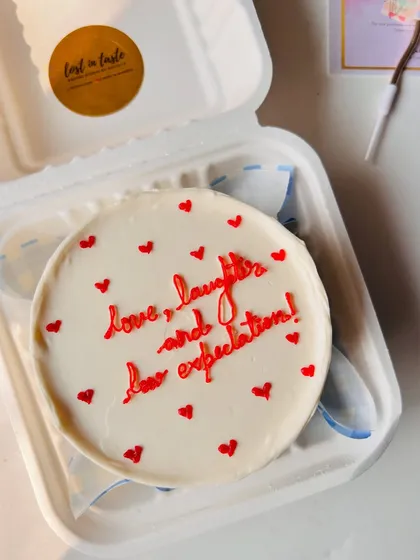 A sweet and simple message for any occasion. This cake features the phrase "love, laughter, and low expectations" in delicate red piping, surrounded by tiny hearts.