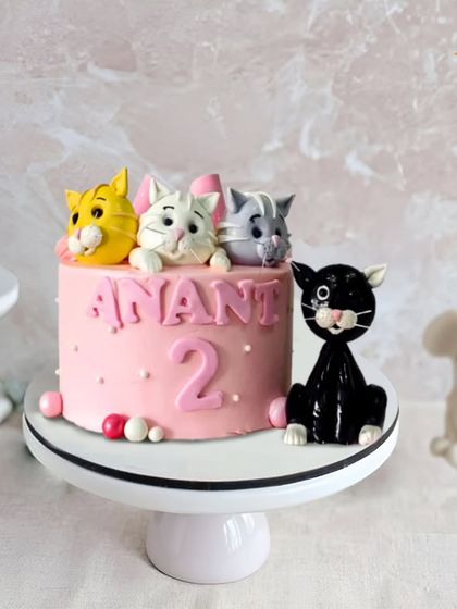 A purr-fectly adorable cat-themed cake for a 2nd birthday. This pink cake is decorated with a family of cute fondant kittens, making it a sweet and charming choice.