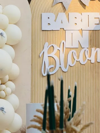 The custom 'Babies in Bloom' signage adds a personalized and stylish touch to the neutral-toned, fluted backdrop.
