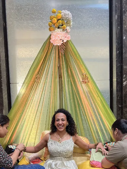 A guest getting her Mehendi done in a specially arranged seating area, showcasing the festive and interactive nature of the event.
