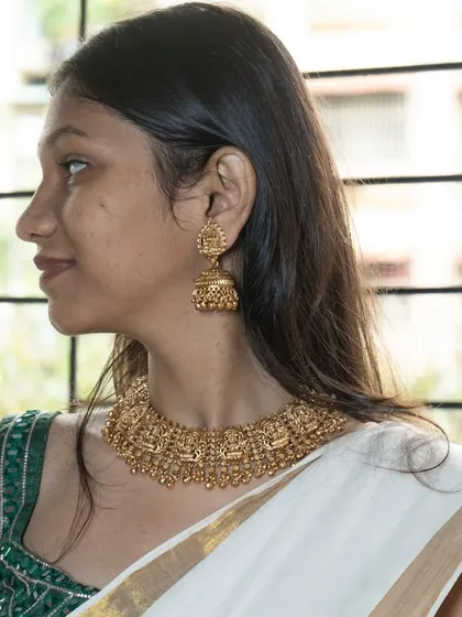 A side profile showcasing the beautiful jhumkas that come with the temple jewellery set. They are designed to be grand yet comfortable to wear.