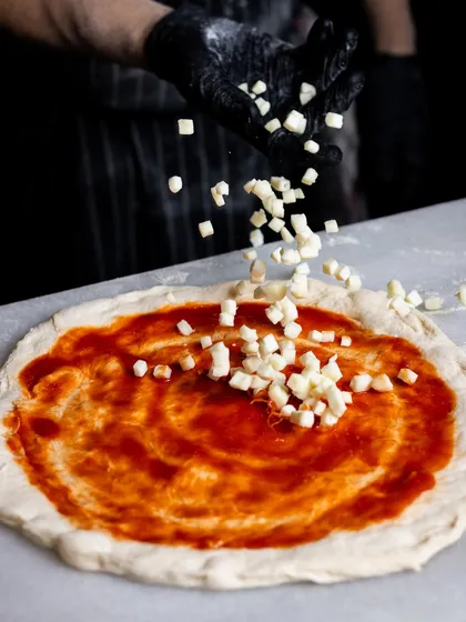 When the sauce meets its match. A generous sprinkle of diced mozzarella cheese is scattered over the tomato sauce, ready for the oven.