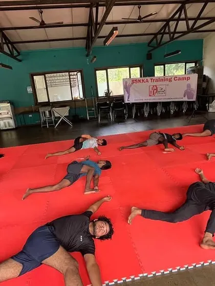 Flexibility is crucial for preventing injuries and executing advanced techniques. This image shows our athletes in a deep stretching pose, working on their hip and leg flexibility as part of our integrated yoga for fighters program.