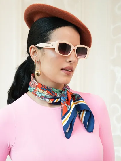 Another angle of the second look from the Crocs campaign. The combination of the bright pink top, printed scarf, and retro sunglasses creates a vibrant and eye-catching commercial fashion look.