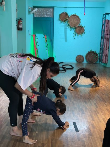 In a busy class, I'm always moving and correcting. Here, I'm helping a student with her forward bend while others work on backbends, ensuring everyone gets the attention they need to progress safely.