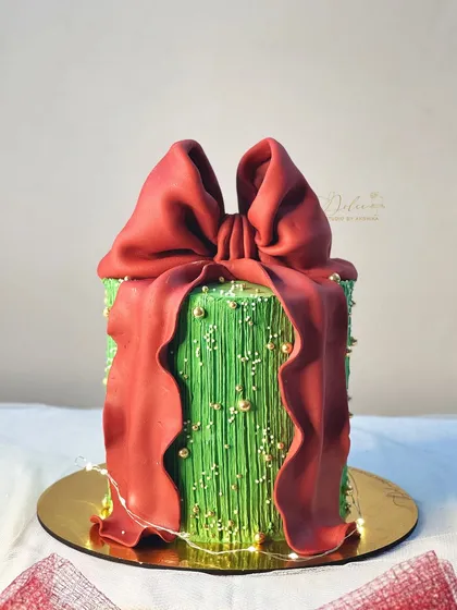 My obsession with fondant bows continues! This Christmas-themed gift box cake features a large, dramatic red bow against a textured green background.