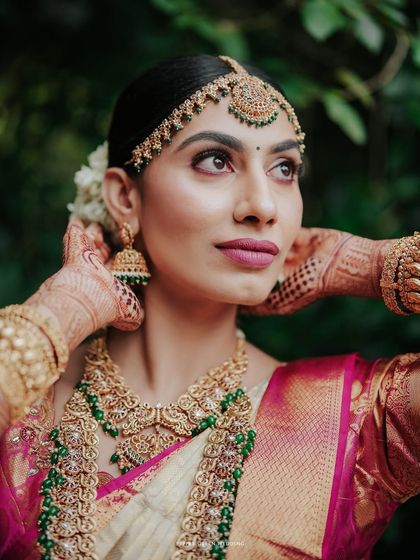 A stunning portrait of the bride, her gaze thoughtful and serene, highlighting her intricate matha patti and traditional jewelry.