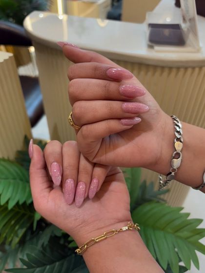 A beautiful set of long, almond-shaped nails with a soft pink glitter polish. This is a great option for adding sparkle in a more understated way.
