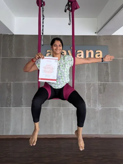Another happy graduate, sitting proudly in the hammock with her well-earned aerial yoga teaching certificate.