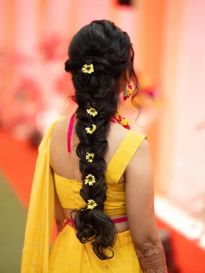 A beautiful braided hairstyle for a Haldi ceremony, adorned with fresh yellow flowers to match the theme.