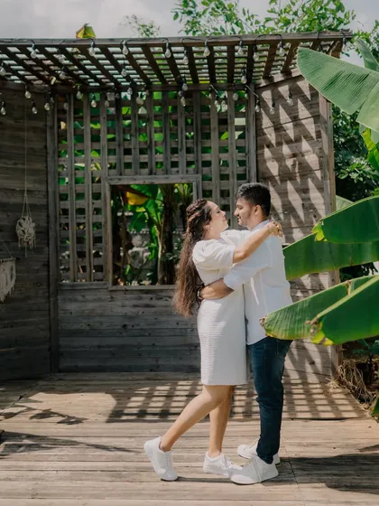 A joyful, interactive shot of the couple dancing on a wooden deck. Their happy expressions and the beautiful, sunny location make this a perfect pre-wedding memory.