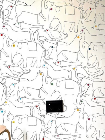 The finished doodle mural, where elephants, horses, birds, and fish mingle in a continuous line drawing. The colorful polka-dot eyes add a touch of playful charm.