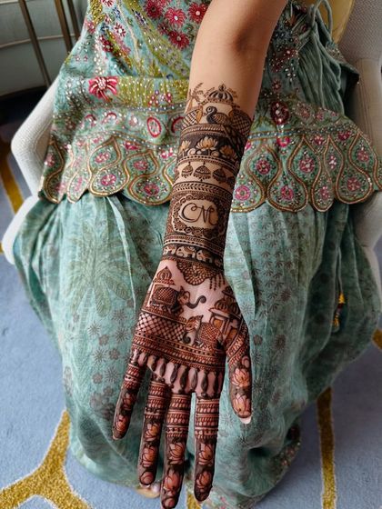 A simple yet elegant way to personalize your mehndi is by including the couple's initials. Here, the 'CM' monogram is beautifully integrated into a traditional band on the forearm.