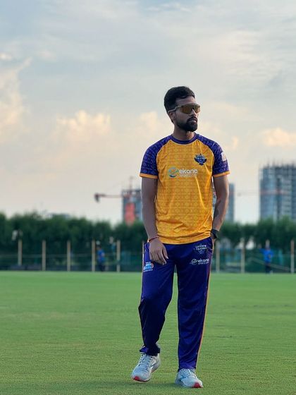 A moment of reflection on the field against the backdrop of a stadium under construction, symbolizing the constant growth and development in the world of cricket.