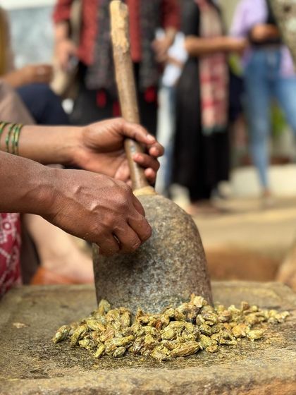 Our artisans demonstrate the traditional method of grinding myrobalan, a natural tannin, in a stone grinder. This ingredient is essential for fixing color in the natural dyeing process, a technique we share in our workshops.