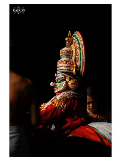 A darkly lit profile of a Kathakali artist, where shadows and light play to create a moody and dramatic portrait.