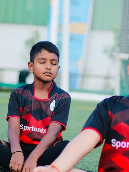 We teach our players that football is about both mind and body. Here, two young athletes take a moment for a cool-down with some light meditation to focus and relax after training.