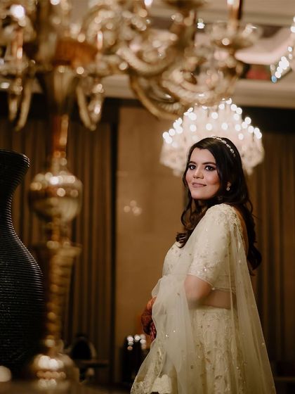 An elegant portrait of the bride at her engagement, with the grand chandeliers of the venue adding a touch of luxury and grandeur to the scene.